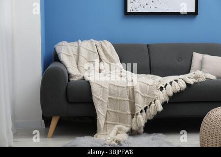 Beige woolen blanket and pillows on sofa indoors Stock Photo