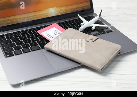 Passport, flight ticket, plane model and laptop on white wooden table, closeup Stock Photo