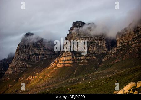 Mist flowing over and in between the majestic peaks of the Twelve Apostle Mountains of the Cape Fold Belt, in South Africa, with their cliffs illumina Stock Photo