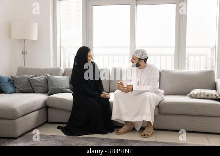 Smiling Arab family couple relaxing talking at home on weekend Stock Photo
