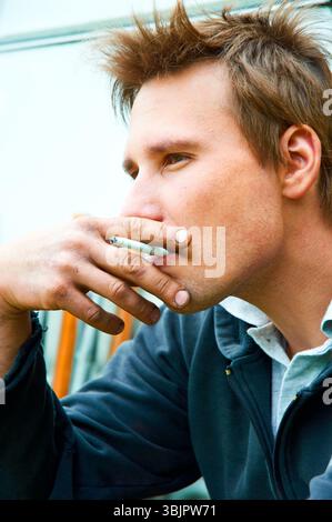 Closeup of a young man with cigarette in mouth Stock Photo