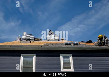Professional roofers applying roofing materials on house exterior, perfect for construction, home improvement and contractor concepts Stock Photo