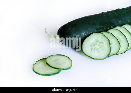 Whole and sliced cucumber in a white background. Salad ingredient. Healthy diet nutrition. Directly above. Stock Photo