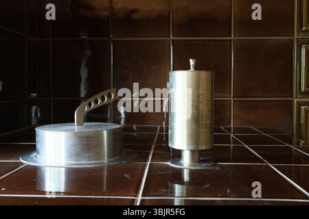 A collection of Vintage Metal Kitchen Utensils displayed elegantly on a Dark Tiled Surface Stock Photo