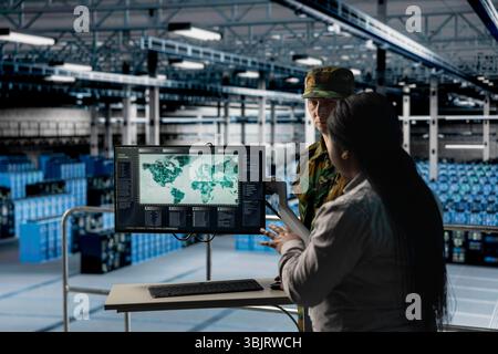 Team of military experts in data center examining mission coverage zones on global mapping software. Army units in server farm confirming strategic priorities using interactive geographic display Stock Photo