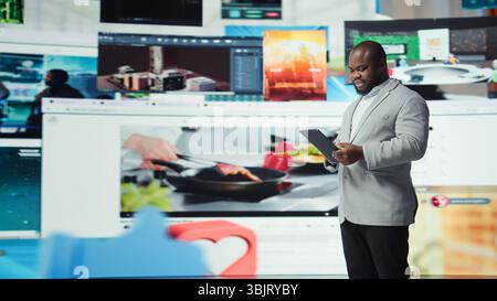 Joyous man using tablet, receiving personalized video recommendations delivered instantly. Upbeat user using device, enjoying digital era enabling unlimited streaming opportunities, camera A Stock Photo