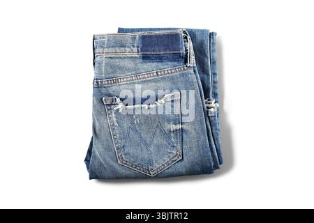 Light-washed ripped denim jeans folded flat on white surface Stock Photo