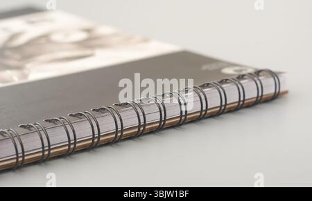 close-up of black metal spiral binding of notebook or sketchpad on gray surface, side view taken in soft focus with copy space Stock Photo