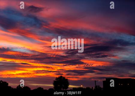 Spectacular sunset sky ablaze with deep orange, red, and purple clouds over the silhouette of the Bayfront Parkway area in Pensacola, Florida. Stock Photo