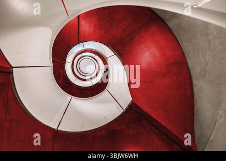 Switzerland - January 16. 2025:: Spiral concrete staircase with red color ceiling in a red residential building Stock Photo