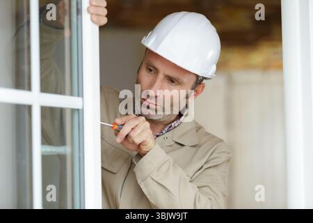 young repairman fixing window frame in room Stock Photo