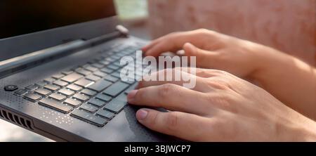 A man works on a laptop outdoors, hands on a keyboard closeup. Stock Photo
