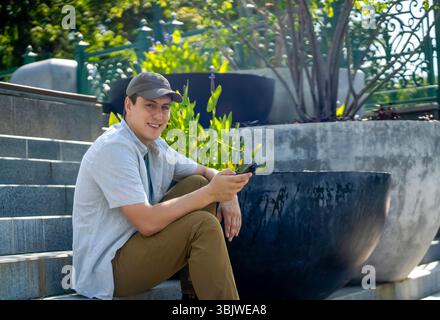 A young happy man talks, communicates on a smart phone outdoors. Stock Photo