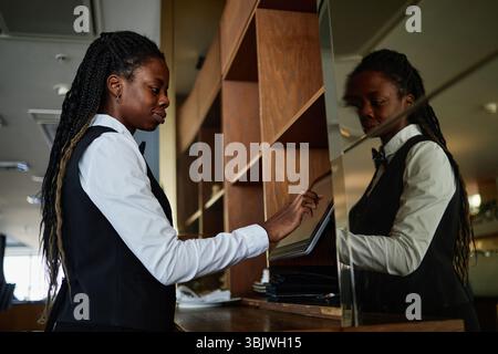 Young Adult Black Woman Restaurant Worker Using Digital Tablet at Counter Stock Photo