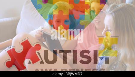 Sharing three preteen girls examining tablet on living room sofa, with autism awareness puzzle Stock Photo