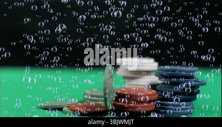 Showing stacks of gaming chips resting on green felt surface, with drifting air bubbles Stock Photo