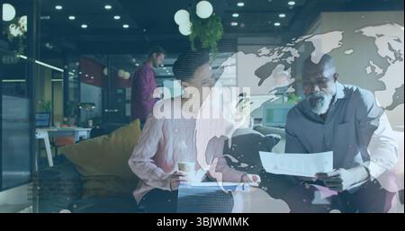 Colleagues in pink sweater and gray shirt discussing documents in office, with pen, coffee cup Stock Photo
