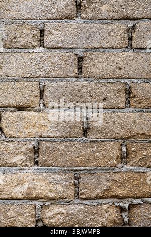 Brick wall with a rough texture and a few holes. The wall is made of gray bricks and has a somewhat worn appearance Stock Photo