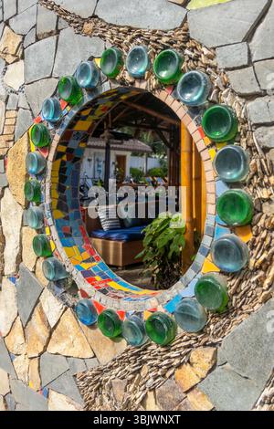 Mosaic wall with green and blue glass pieces. The mirror is surrounded by a wall made of stone and glass Stock Photo
