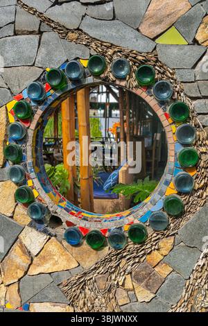 Mosaic wall with green and blue glass pieces. The mirror is surrounded by a wall made of stone and glass Stock Photo