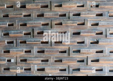 Brick wall with many holes in it. The wall is made of wood and has a rough texture Stock Photo