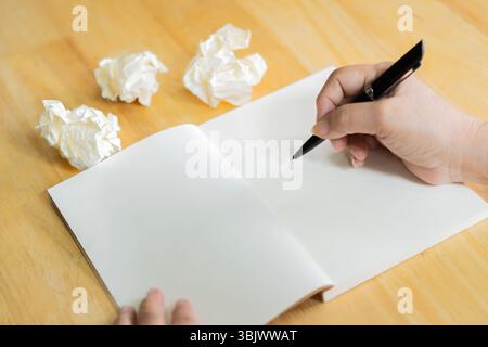 Elderly hands holding a blank paper and pen with space for writing a letter on wooden table. Back view. Stock Photo