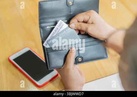 Rear view of mature woman with credit cards making mobile payment at cafe. Shopping online payment concept. Stock Photo