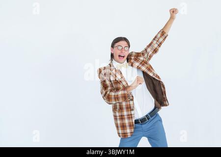 Man wearing plaid blazer and yellow bow tie celebrating with fist pump in studio, copy space Stock Photo