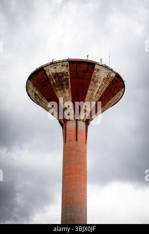 Old Red and White Water Tower Against Cloudy Sky on Overcast Day. Stock Photo