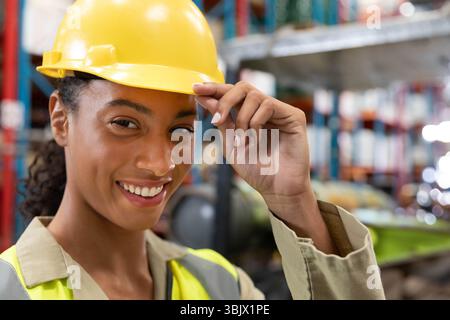 Worker wearing yellow hard hat and hi-vis vest in warehouse with racks and boxes Stock Photo