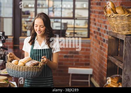 assorted breads sitting in woven basket on wooden countertop in bakery, showcasing brick textures Stock Photo