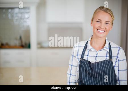 Wooden counter running through home kitchen with subway-tile backsplash and utensils, copy space Stock Photo