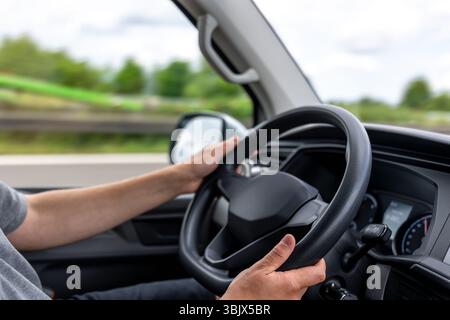 Hands on steering wheel. Driver holding wheel. Car control in motion. Stock Photo