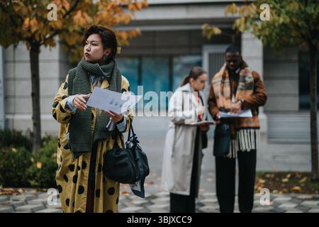 Multiracial team collaborating and analyzing business documents outdoors on a fall day Stock Photo