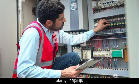 Electrical engineer inspects the electrical control board of a crane before putting it to use on a construction site Stock Photo