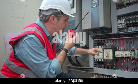 Electrical engineer inspects the electrical control board of a crane before putting it to use on a construction site Stock Photo