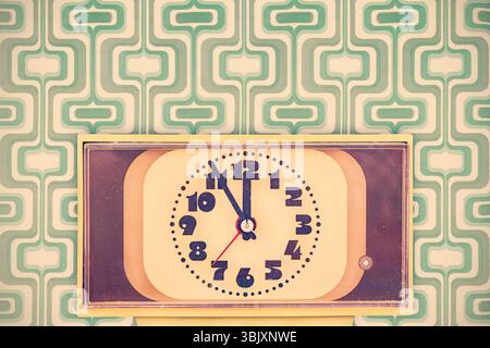 Retro styled image of a seventies alarm clock in front of vintage wallpaper Stock Photo