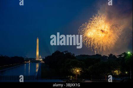 Yellow fireworks explode over the National Mall at night as the Washington Monument stands in the background, lighting up the sky during a public cele Stock Photo