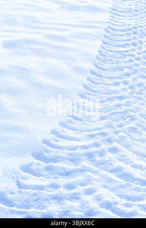 Tractor clear trail tracks in snow blue tone sunny day background Stock Photo