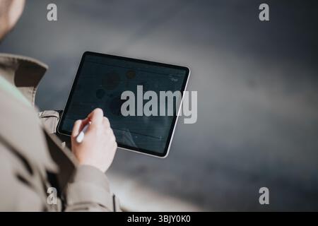 Close-up of a person using a tablet with a stylus for data analysis in a professional setting. Stock Photo