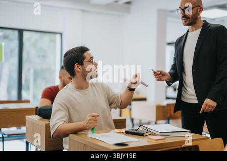 Teacher assisting high school student during classroom activity Stock Photo