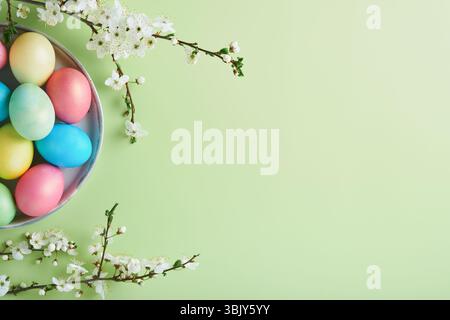Happy Easter. Dyed Easter eggs on rustic table with cherry blossom tree branch on green background. Easter holiday card backgrou Stock Photo