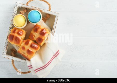Easter hot cross buns with colored eggs, Easter gingerbread rabbits and cookies over white plank wooden old table background . S Stock Photo