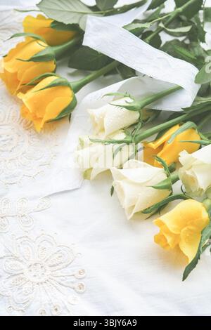 Happy Easter. Easter eggs on rustic table with white and yellow roses. Natural dyed colorful eggs in wooden plate and spring flo Stock Photo