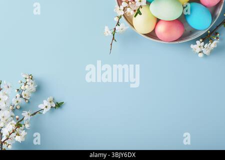 Happy Easter. Dyed Easter eggs on rustic table with cherry blossom tree branch on blue background. Easter holiday card backgroun Stock Photo