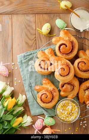 Easter breakfast Holliday concept. Easter bunny buns rolls with cinnamon made from yeast dough with orange glaze, easter decorat Stock Photo