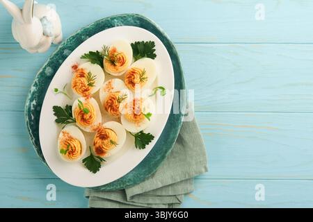 Stuffed or deviled eggs with paprika and parsley on blue plate for easter table. Traditional dish for Easter. Healthy diet food Stock Photo