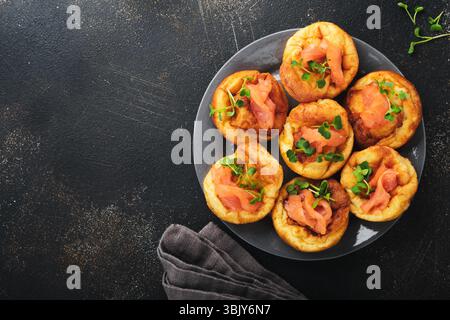 Yorkshire pudding. Traditional English Yorkshire pudding with salmon and radish microgreens side dish on dark grey plate and dar Stock Photo