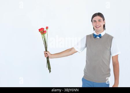 Man wearing gray sweater vest and bow tie holding long-stem red roses in studio, copy space Stock Photo