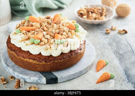 Easter Carrot cake with cream cheese frosting. Delicious carrot cake with walnut and cream cheese frosting on gray concrete back Stock Photo